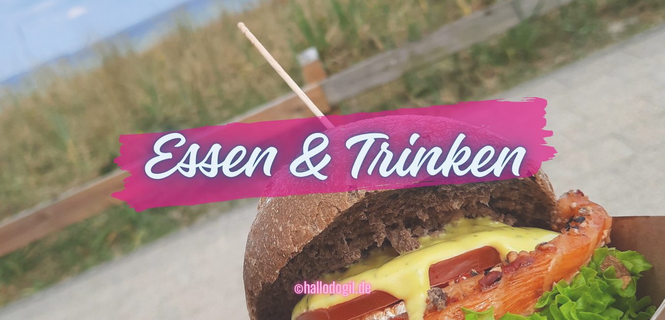 Banner für den Hub Essen & trinken - typische deutsche Essen. Auf dem Bild ein Fischbrötchen am Meer.