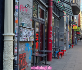 Mauser mit Graffitis und Stickers in der Sternschanze. Daneben eine mit Stuck verzierte weiße Säule